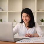 Attractive young businesswoman working with laptop and document at corporate office.