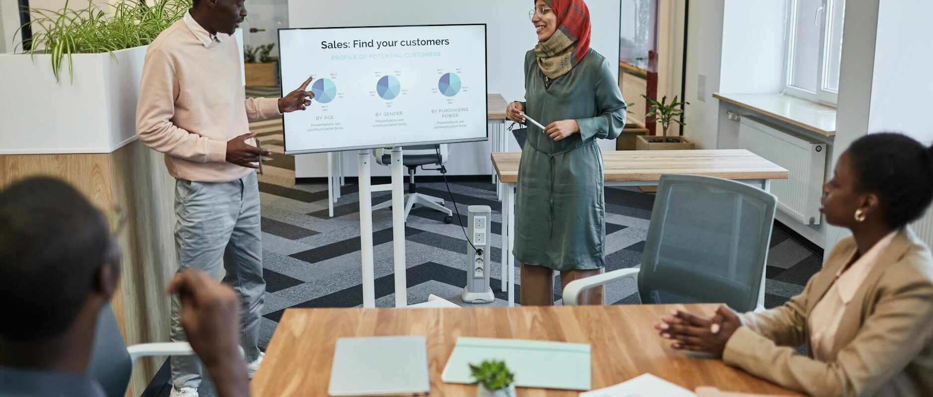 A diverse team engaging in a business meeting focused on sales strategy with visual aids.