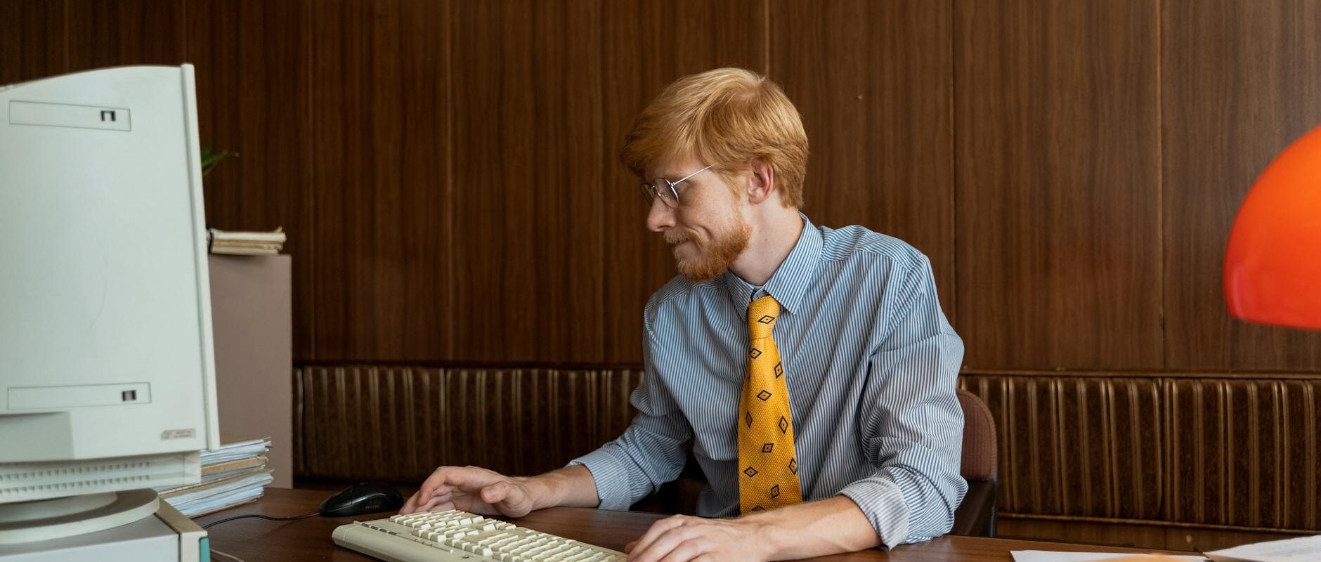 Man in 80s office setting working at old computer, embodying retro business vibes.