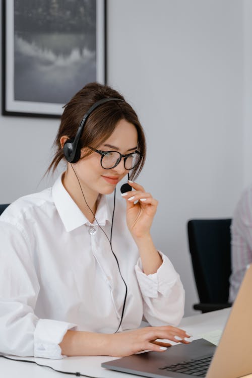 Customer service representative wearing headset working on laptop