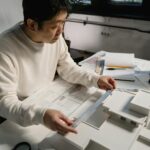 Architect examining architectural scale model with precision tools