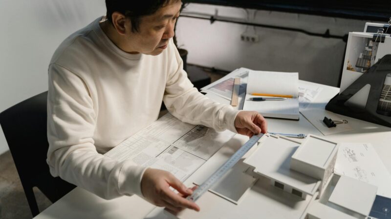 Architect examining architectural scale model with precision tools