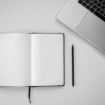 Open notebook, laptop and pen on desk — planning a virtual assistant hire