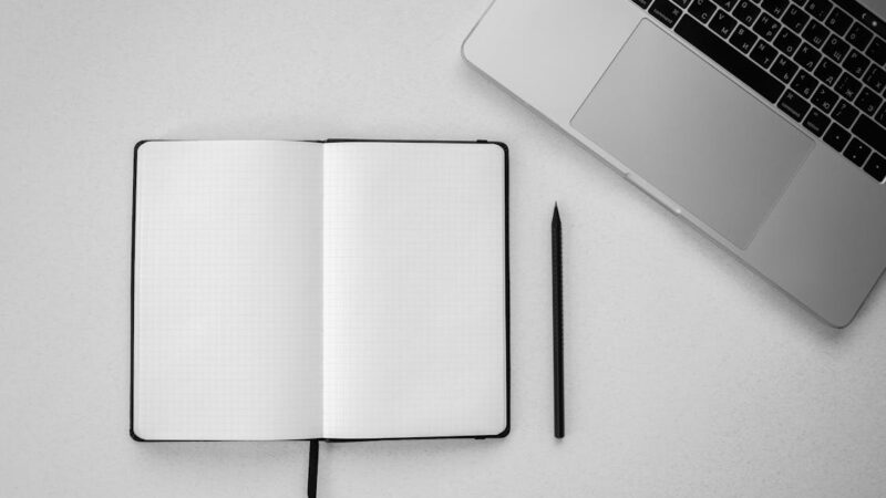 Open notebook, laptop and pen on desk — planning a virtual assistant hire