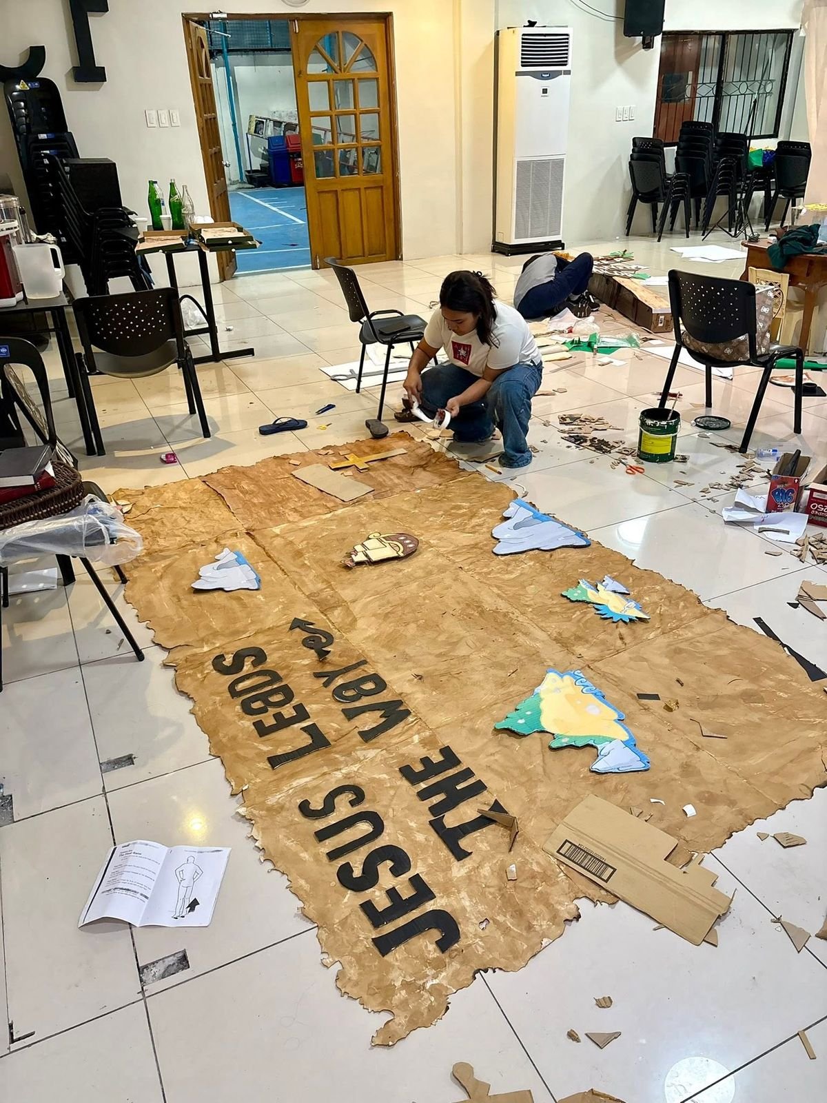 Volunteer hand-painting the giant Treasure Hunt map backdrop for DVBS 2026
