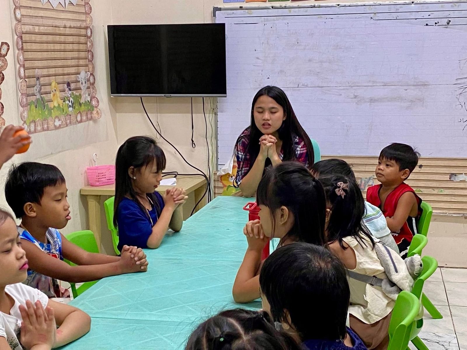 Teacher praying with children in a small group at DVBS 2026