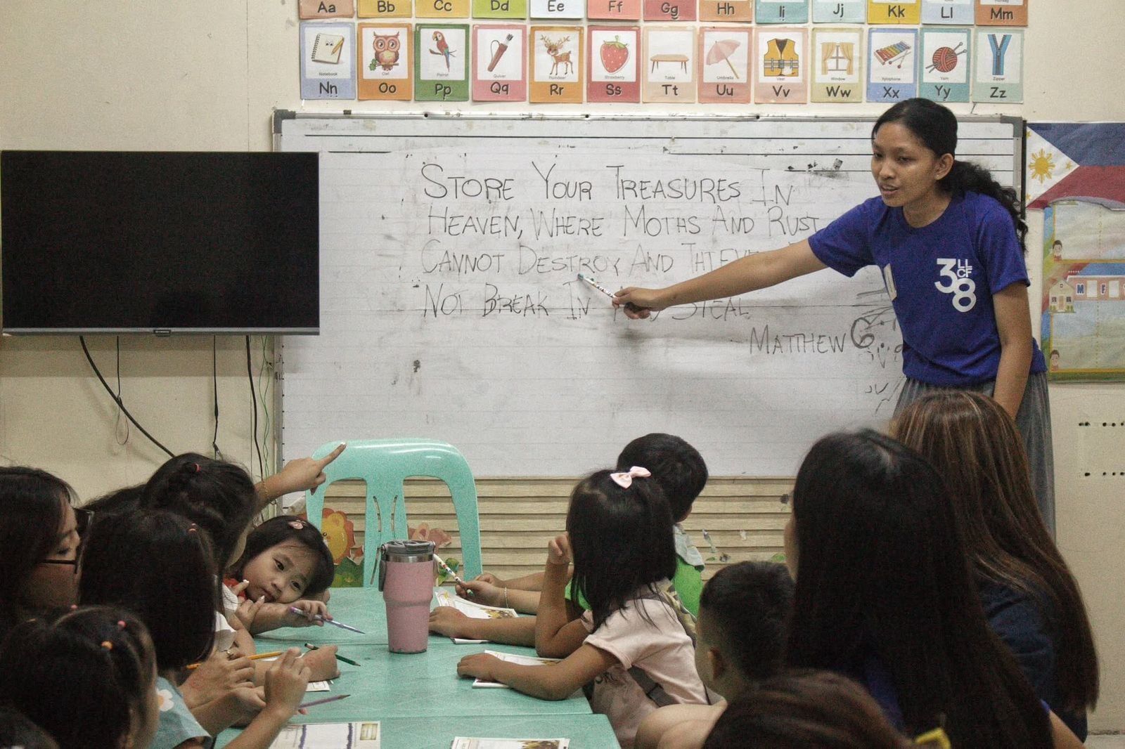 Teacher pointing to the Matthew 6:20 memory verse on the whiteboard