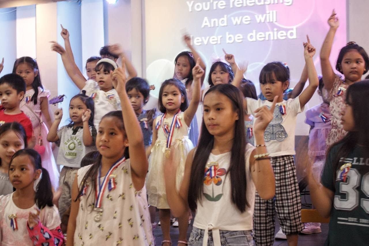Children wearing medals singing worship at the DVBS 2026 closing