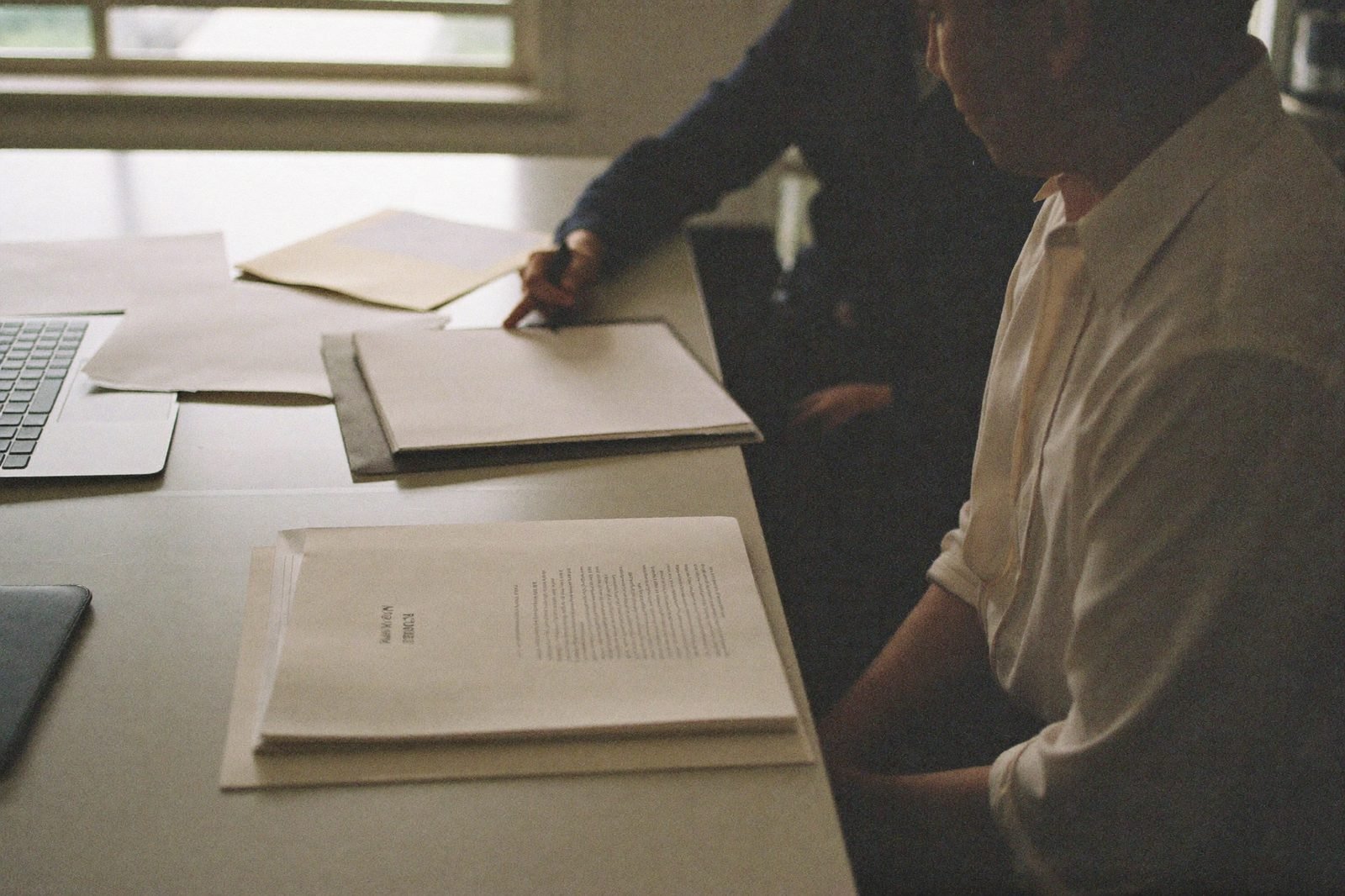 Two attorneys reviewing printed vendor shortlists at a law firm conference table