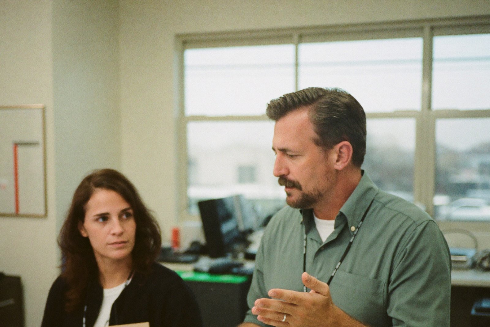 Two real estate agents at a brokerage office counter comparing vendor options