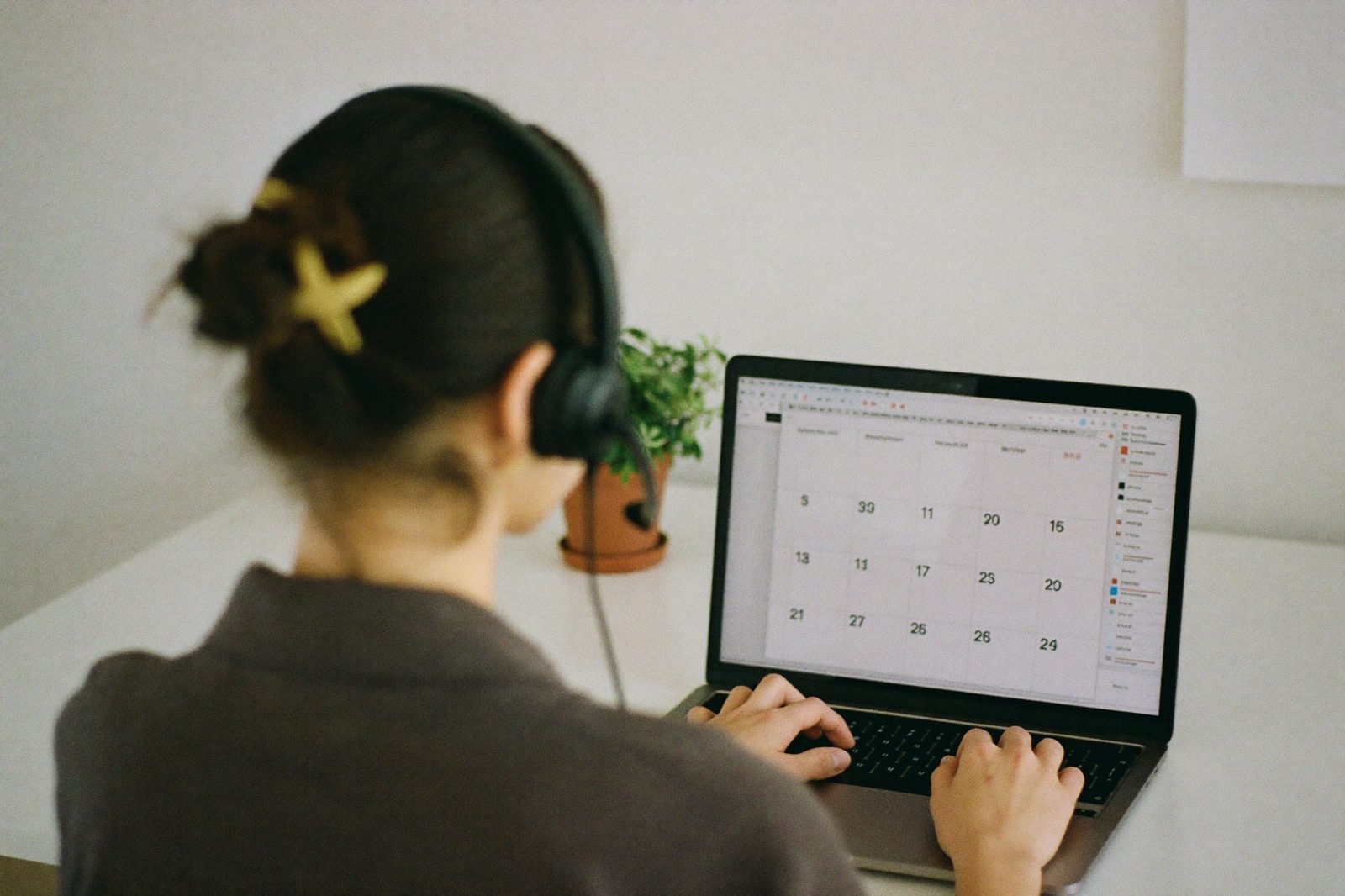 Remote med spa virtual assistant with a headset managing a calendar on a laptop