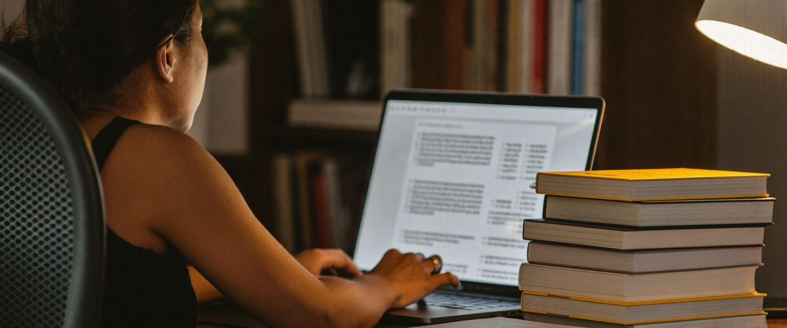 Filipina author virtual assistant working late with books and a laptop