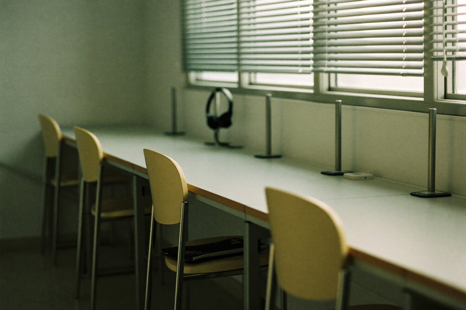 Row of empty desks with headsets on stands in an outbound calling team room