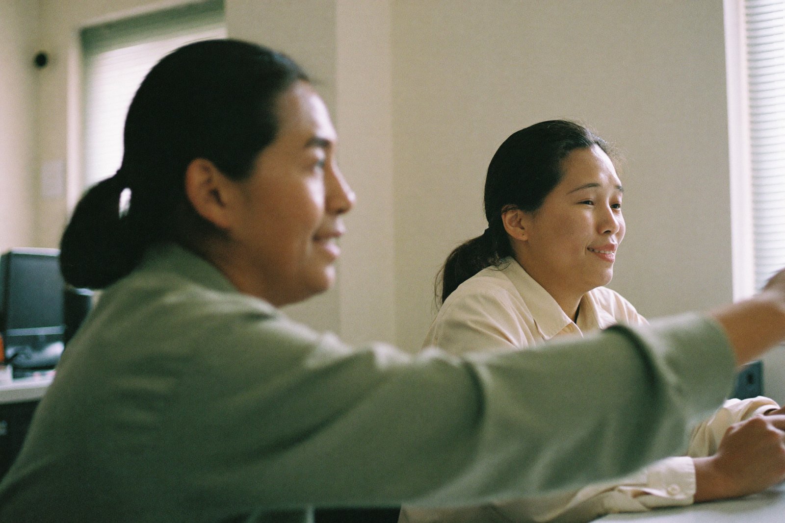 Two Filipino colleagues working side by side at one desk in a Manila office